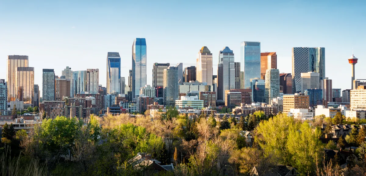Downtown Calgary skyline above a tree-lined riverbank